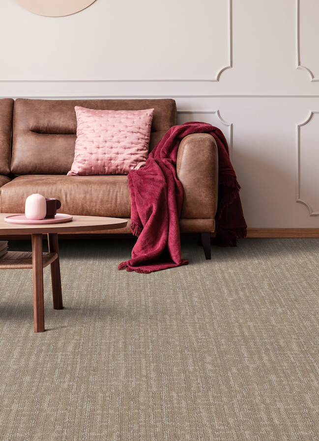 brown textured carpets in a living room with pink accents and a brown leather couch